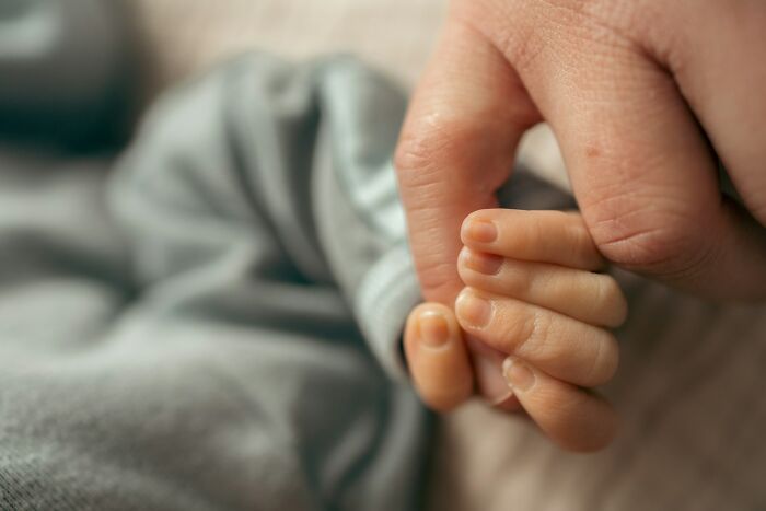 Adult hand gently holding a baby's hand, symbolizing care and connection in comically absurd facts context.