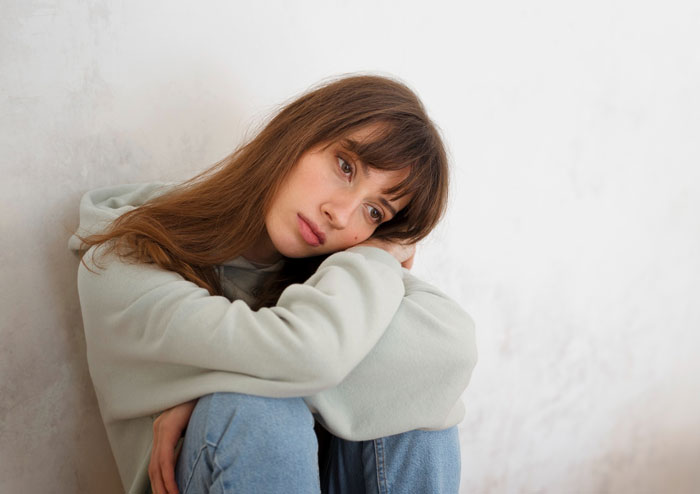 Young woman in casual clothes looking pensive and sad, reflecting on an evil stepmom&rsquo;s failed life and poetic justice.