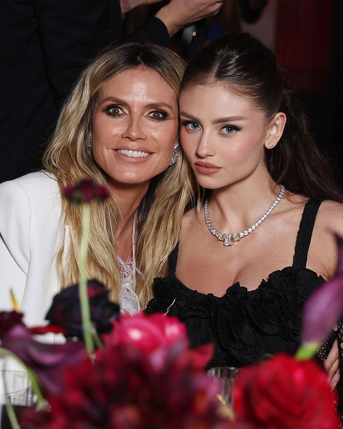 Heidi Klum and daughter Leni posing together in elegant outfits with bold lingerie shoot theme and floral foreground.