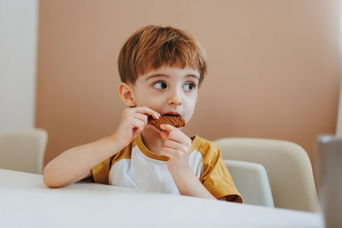Young child eating a cookie at a table, illustrating common ways parents fail at raising kids in everyday moments.
