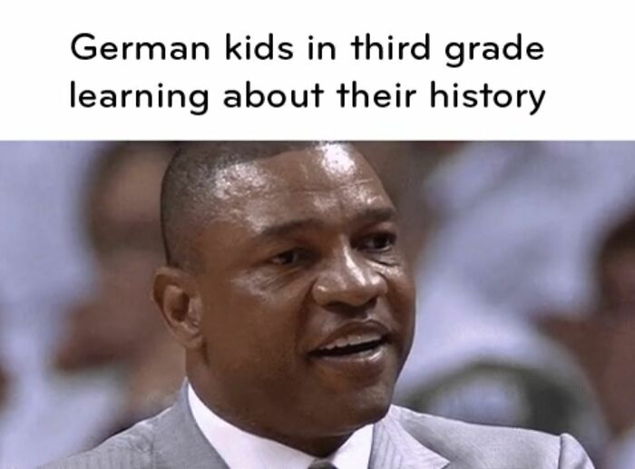 Man in suit reacting with interest, captioned about German kids in third grade learning history, history memes concept.