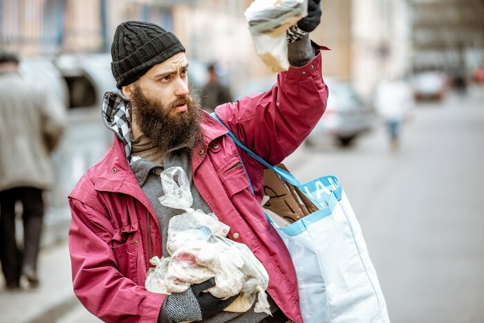 Bearded man in a red jacket holding bags and looking surprised, illustrating crazy coincidences people experienced.