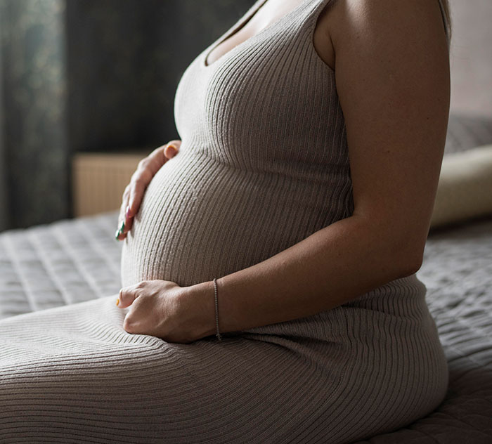 Pregnant woman sitting on bed, highlighting mysteries about the human body that science still has not explained.