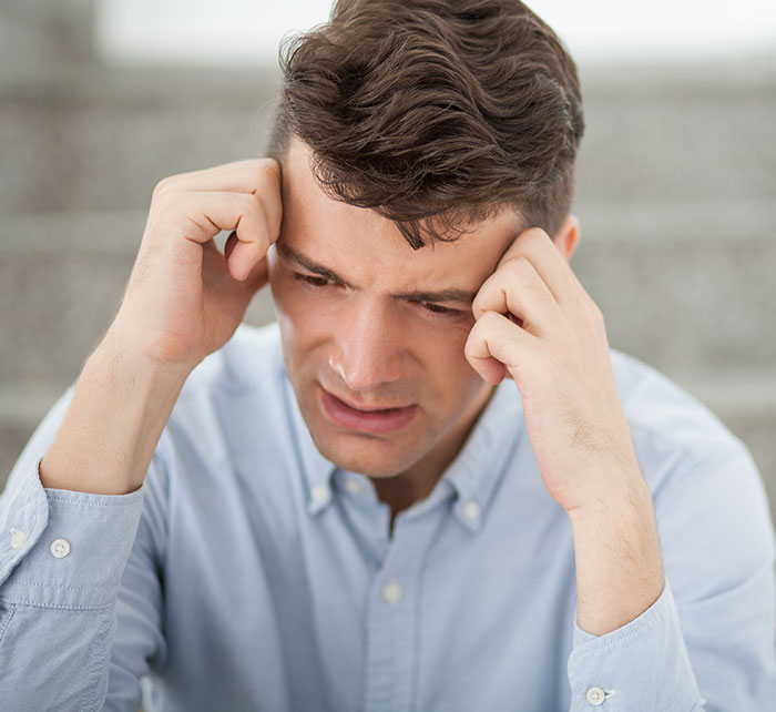Young man holding his head in frustration, illustrating the mysteries about the human body that science cannot explain.