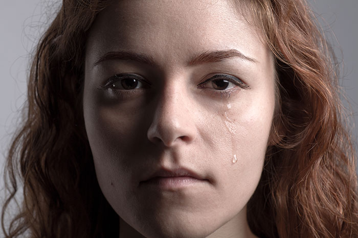 Close-up of a young woman with tears on her face, illustrating mysteries about the human body that science still hasn't explained.