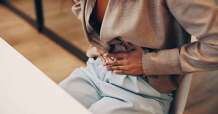 Person sitting and holding their stomach, illustrating unexplained mysteries about the human body by science.