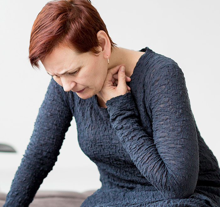 Middle-aged woman with short hair touching her neck, illustrating mysteries about the human body unexplained by science.