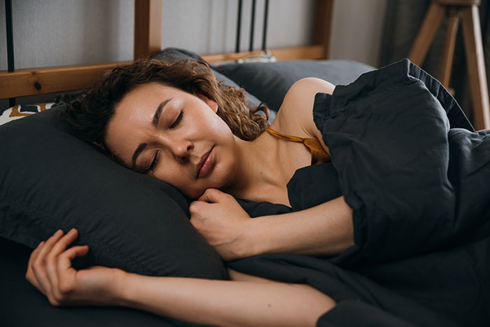 Woman sleeping peacefully in bed, illustrating one of the mysteries about the human body that science still hasn't explained.