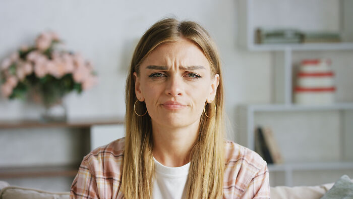 Suspicious woman expressing doubt and concern while sitting indoors, reflecting feelings of something being off in relationship.
