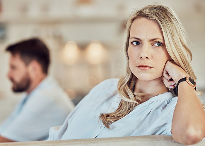 Wife looking suspicious and upset while man sits in the background, highlighting master&rsquo;s degree lie discovery story.