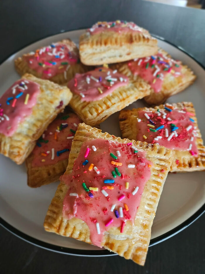 Plate of gorgeous baked goods topped with pink icing and colorful sprinkles, showcasing creative kitchen magic.
