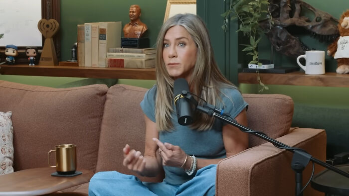 Woman speaking into microphone on couch in casual setting, sharing stories about meeting James Franco in person.