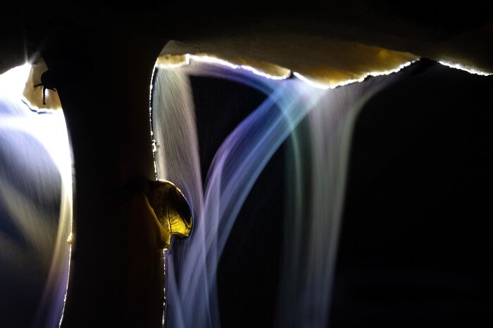 Close-up of glowing water streams flowing from rocks in a dark setting, showcasing nature photography in impressive detail.