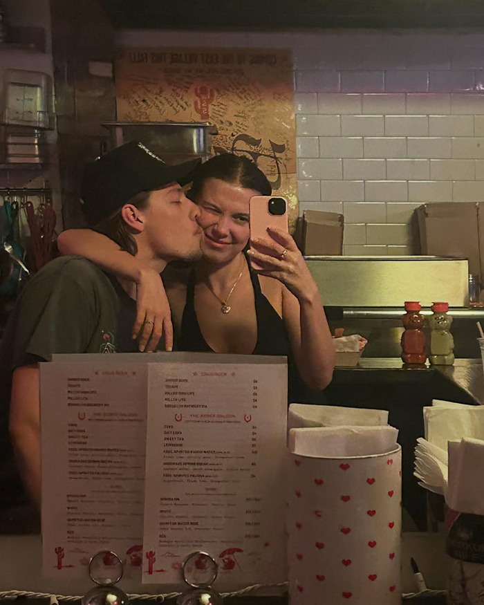 Jake Bongiovi kissing Millie Bobby Brown while taking a selfie, highlighting criticism about not helping protect their baby.