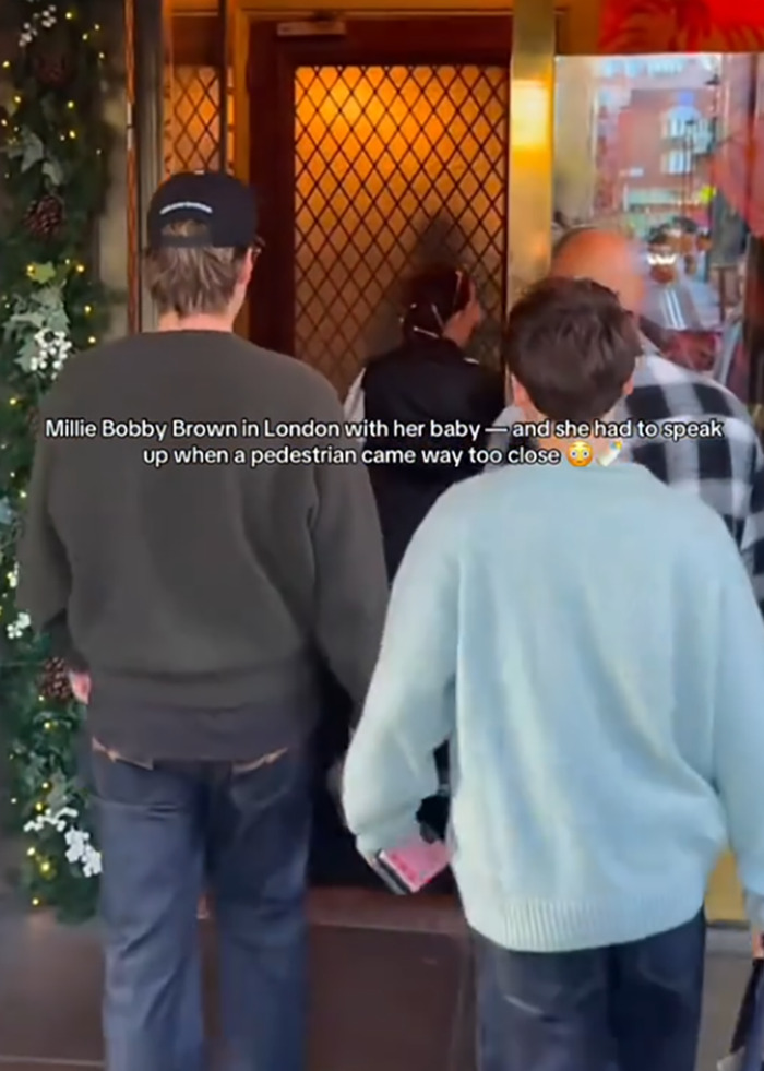 Jake Bongiovi criticized for not helping while Millie Bobby Brown protects their baby outside building in London.