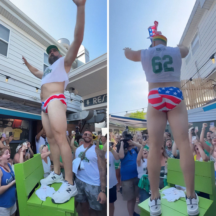 Man in patriotic underwear and cropped top dancing energetically at crowded outdoor party, sparking celebrity reveal frenzy.
