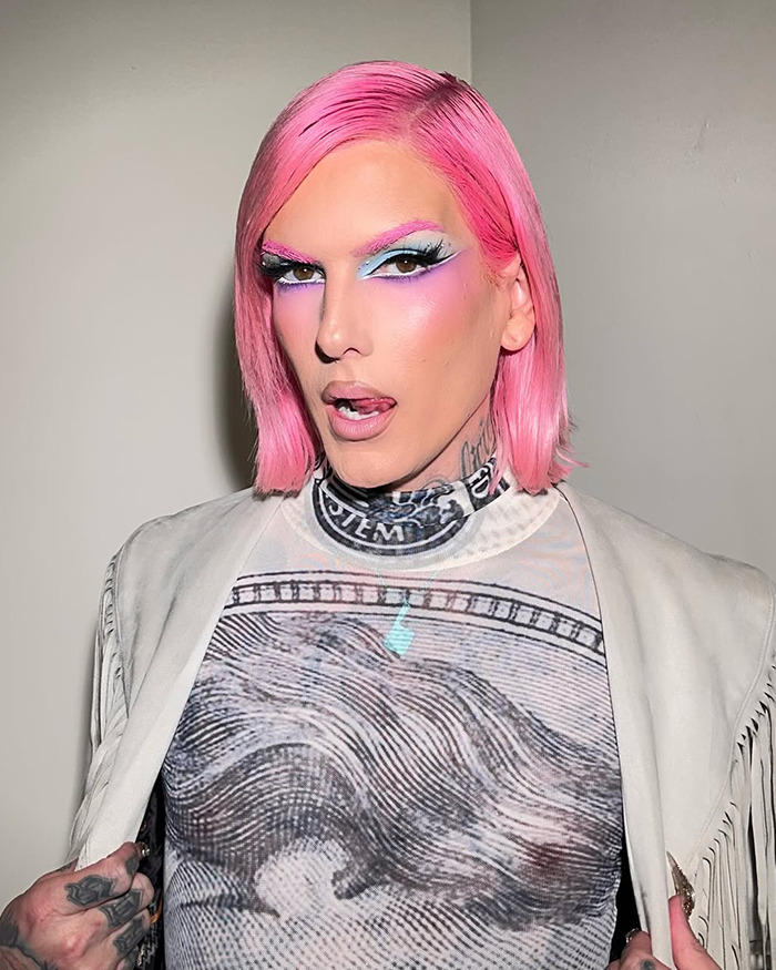 Jeffree Star with pink hair and bold makeup, posing against a plain background amid backlash over pro-trans parents comments.