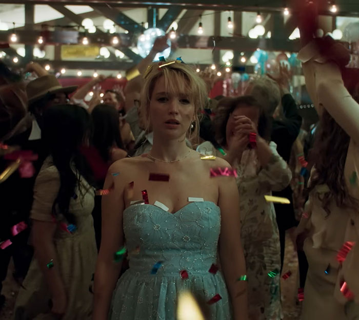 Jennifer Lawrence standing in a blue dress at a crowded party with confetti falling around, capturing intimate moments.