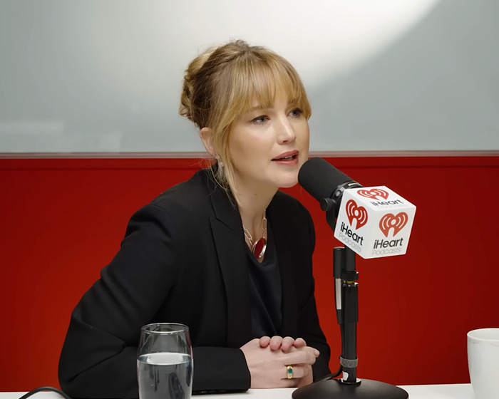 Jennifer Lawrence speaking into a microphone during an iHeart podcast interview about male co-stars punishing her.