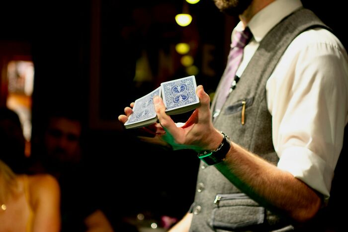 Man in vest and tie performing a card trick, illustrating absurd but true stories about receiving a car as a tip.
