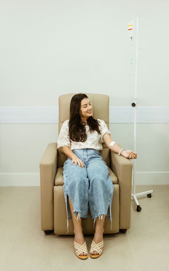 Young woman in casual clothes receiving an IV drip while sharing mysterious medical issues and clear diagnoses