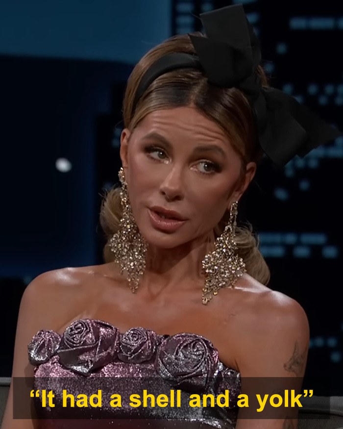Kate Beckinsale wearing a large bow headband and sparkling earrings during a nighttime interview setting. Kate Beckinsale wearing a large bow headband and sparkling earrings during a nighttime interview setting.