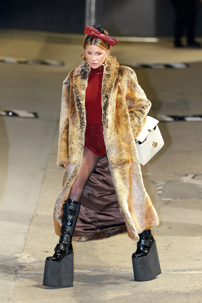 Kate Beckinsale wearing a fur coat and platform boots, walking confidently on a city sidewalk at night. Kate Beckinsale wearing a fur coat and platform boots, walking confidently on a city sidewalk at night.