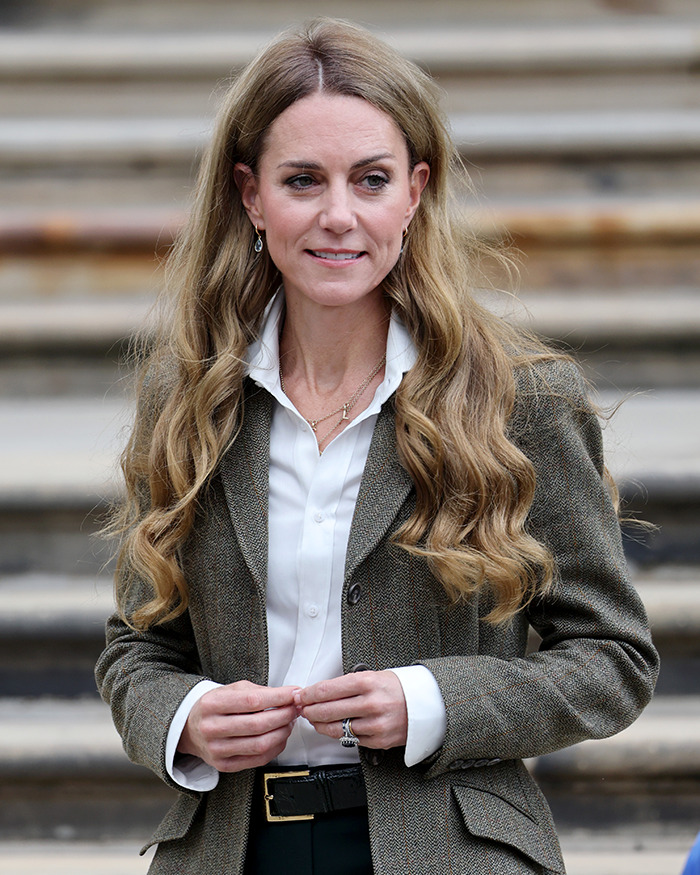Kate Middleton with long, healthy hair styled in loose waves, wearing a white shirt and tweed blazer outdoors.