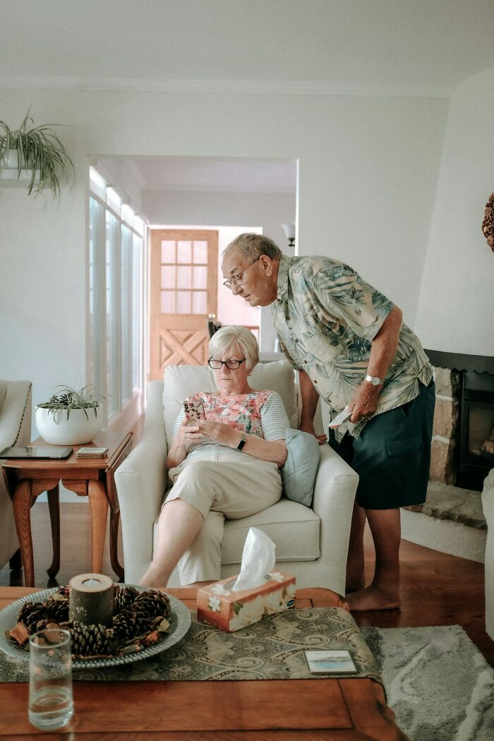 Older couple in living room looking concerned at a mobile phone, illustrating how people fell for scams and their effects.