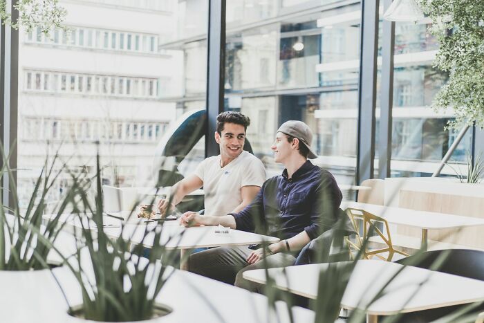 Two young men sitting and chatting in a bright cafe, illustrating culture shocks people experience while visiting Australia.
