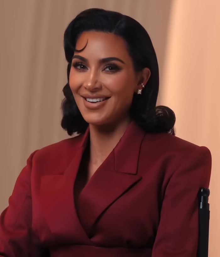 Kim Kardashian smiling in a red blazer during an interview discussing pathological liars and psychic controversies. Kim Kardashian smiling in a red blazer during an interview discussing pathological liars and psychic controversies.