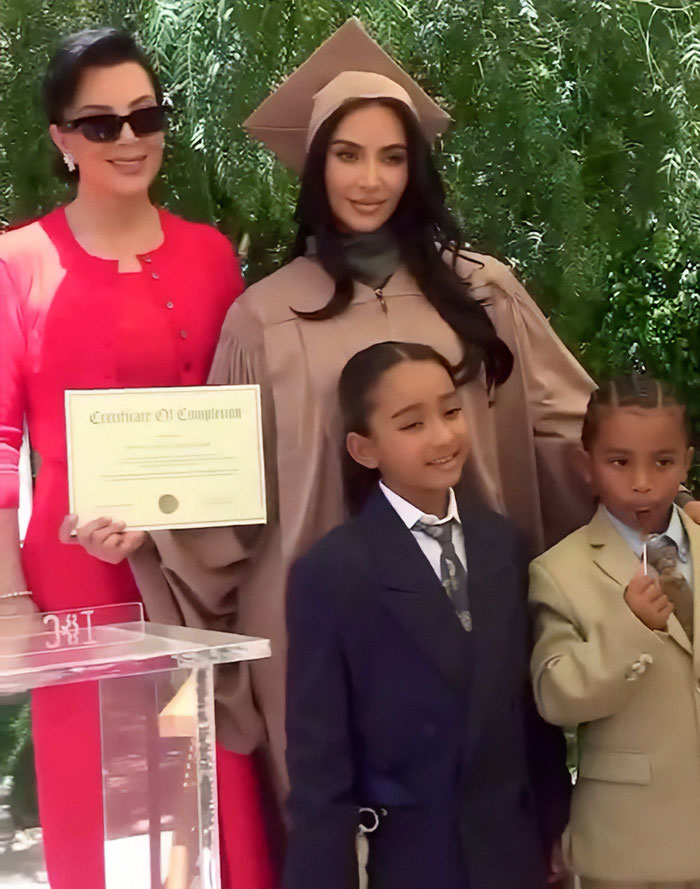 Kim Kardashian in graduation gown with family at outdoor event, highlighting pathological liars theme. Kim Kardashian in graduation gown with family at outdoor event, highlighting pathological liars theme.