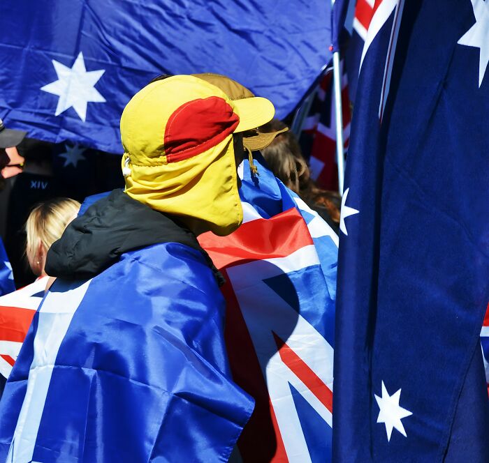 People wrapped in Australian flags at an outdoor event showcasing culture shocks experienced while visiting Australia