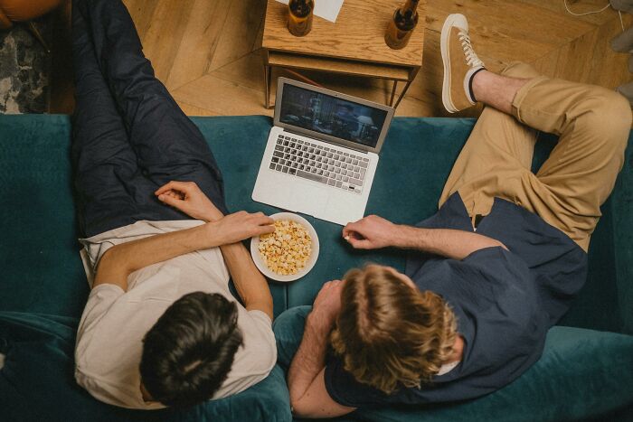 Two people on a couch sharing popcorn while watching a laptop, discussing interesting laws and legal loopholes.