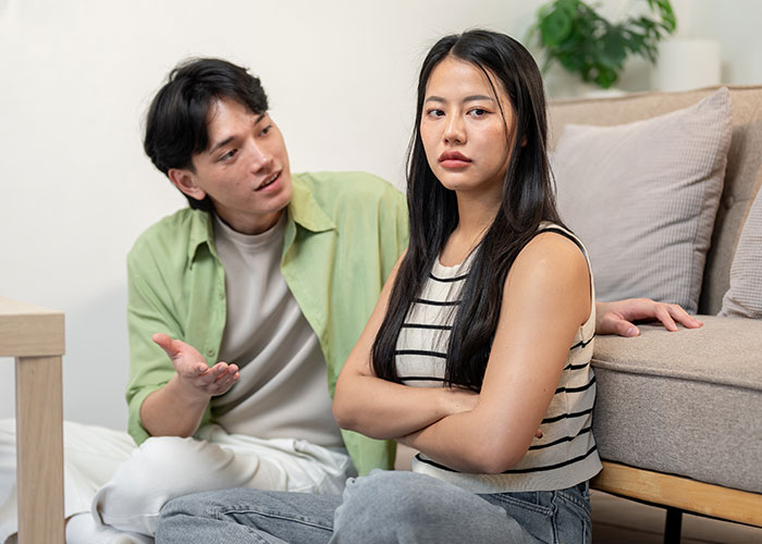 A man and woman sitting on the floor having a tense conversation, illustrating people sharing things learned late in life.