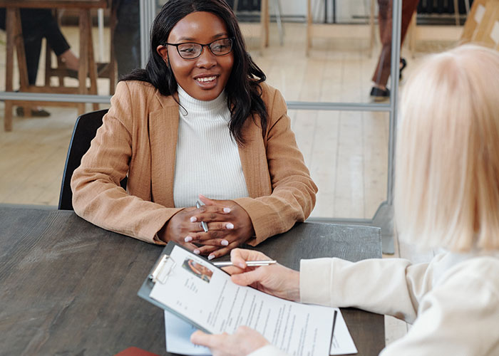 Two women in a job interview setting, sharing insights and life lessons during a professional conversation.
