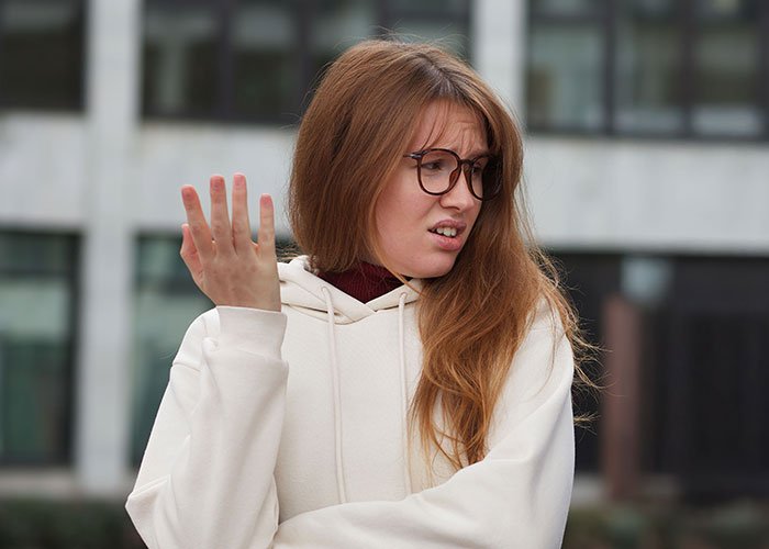 Young woman with glasses making a confused gesture, illustrating things people learned embarrassingly late in life.