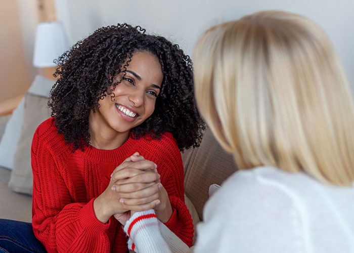 Two women smiling and holding hands during a heartfelt conversation about things learned embarrassingly late in life.