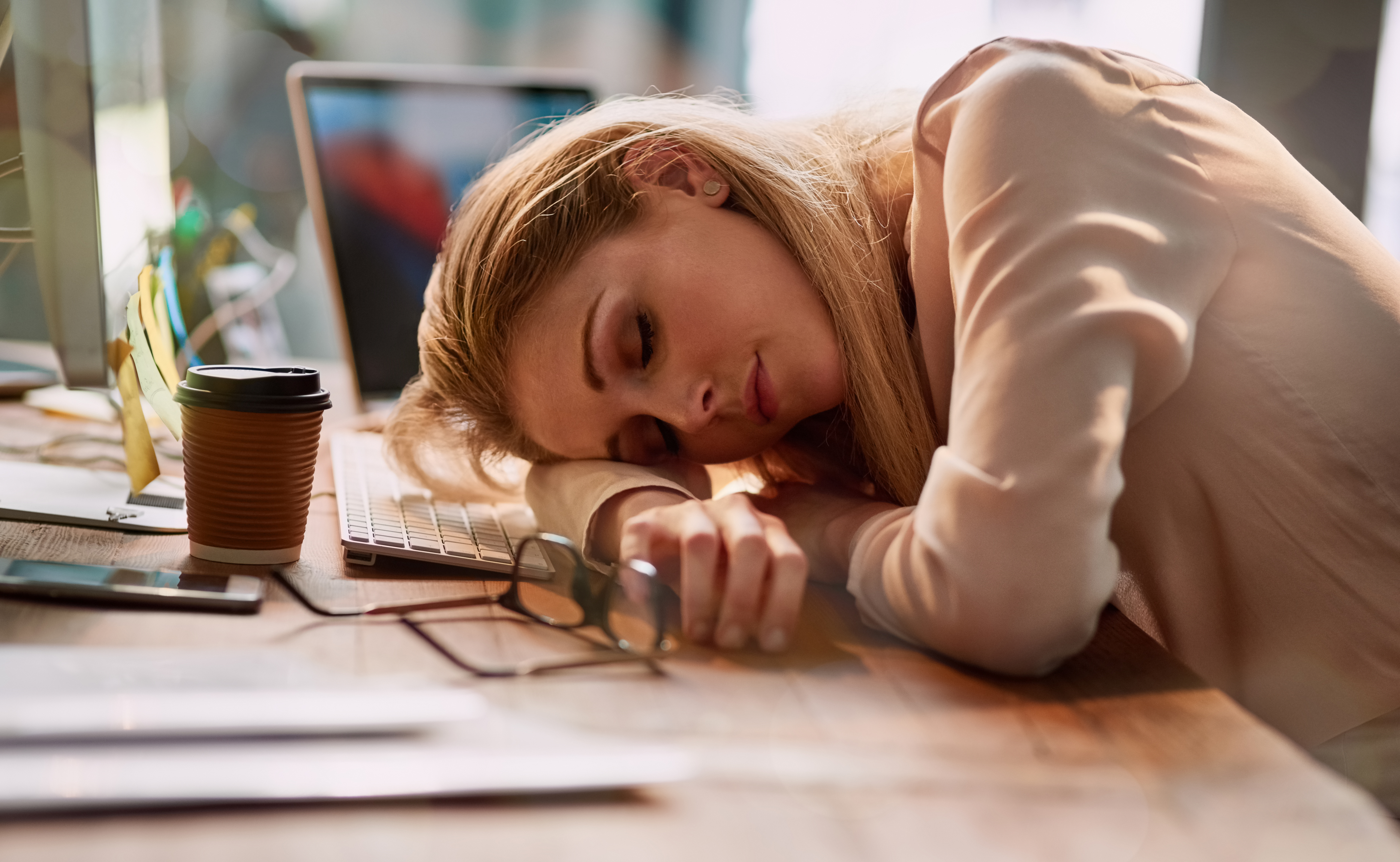 Woman exhausted and resting head on desk, showing effects of being treated like a servant and loss of attraction in relationship.