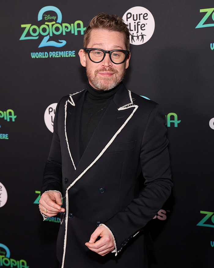 Man wearing glasses and a black suit with white trim attending the Zootopia world premiere event. Man wearing glasses and a black suit with white trim attending the Zootopia world premiere event.