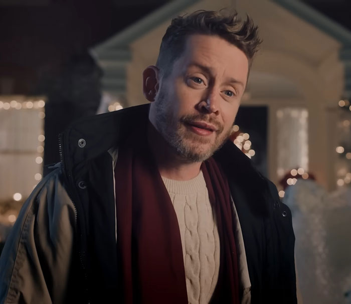 Macaulay Culkin outdoors wearing a coat and scarf, reminding fans about his legal name change.