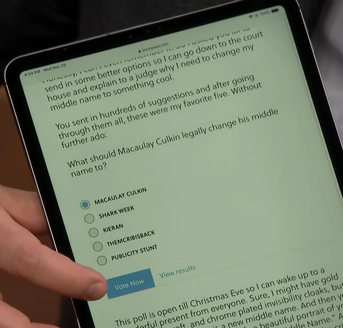 Person holding tablet showing a poll about Macaulay Culkin legally changing his middle name online.