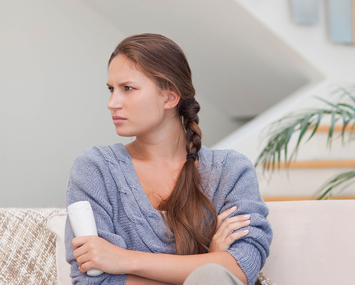 Woman ask stepchildren about home boarding school, sitting with crossed arms and concerned expression indoors.