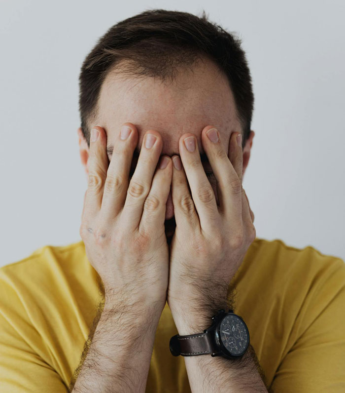 Man in yellow shirt covering face with hands showing frustration in family surprise Christmas story context.