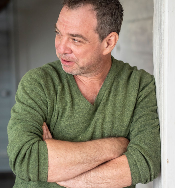 Man in green sweater looking away with crossed arms, reflecting on being mistaken as a free babysitter for girlfriend's son