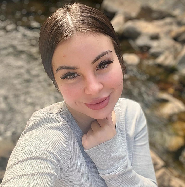 Young woman smiling outdoors by a rocky stream, related to singer DELAROSA news about a gruesome ambush in LA. Young woman smiling outdoors by a rocky stream, related to singer DELAROSA news about a gruesome ambush in LA.