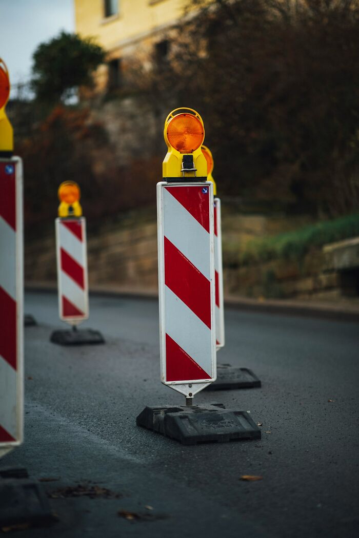 Road construction barriers with flashing lights on an empty street reflecting haunting things truckers have seen on the road at night.