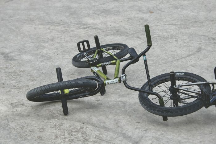 Green and black BMX bike lying on concrete ground, illustrating workers share unprofessional things done concept.