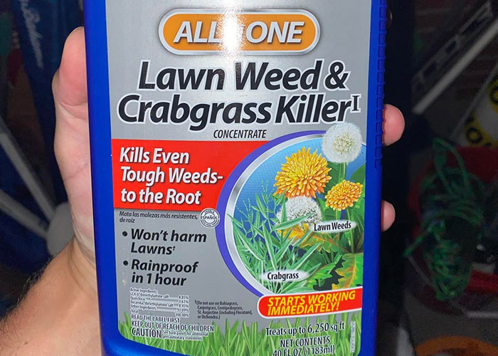 Hand holding lawn weed and crabgrass killer bottle, highlighting dangers of everyday chemical exposure in medical malpractice cases.