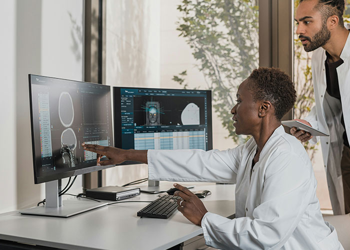 Medical malpractice lawyer reviews CT scans and discusses dangerous things in everyday life with a colleague in an office setting.